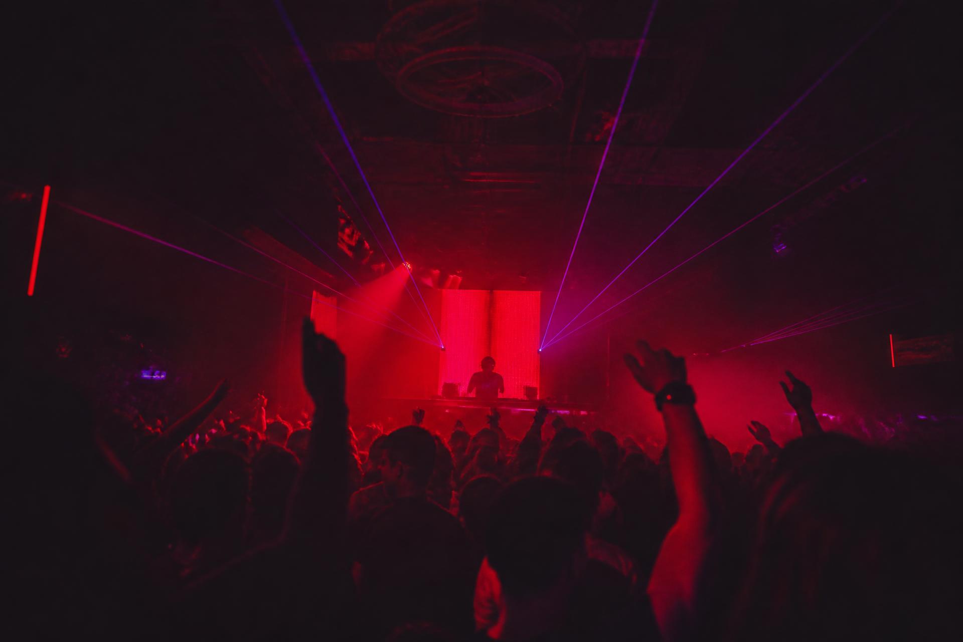 Crowd under red and violet lasers at a NOVA NIGHTS event